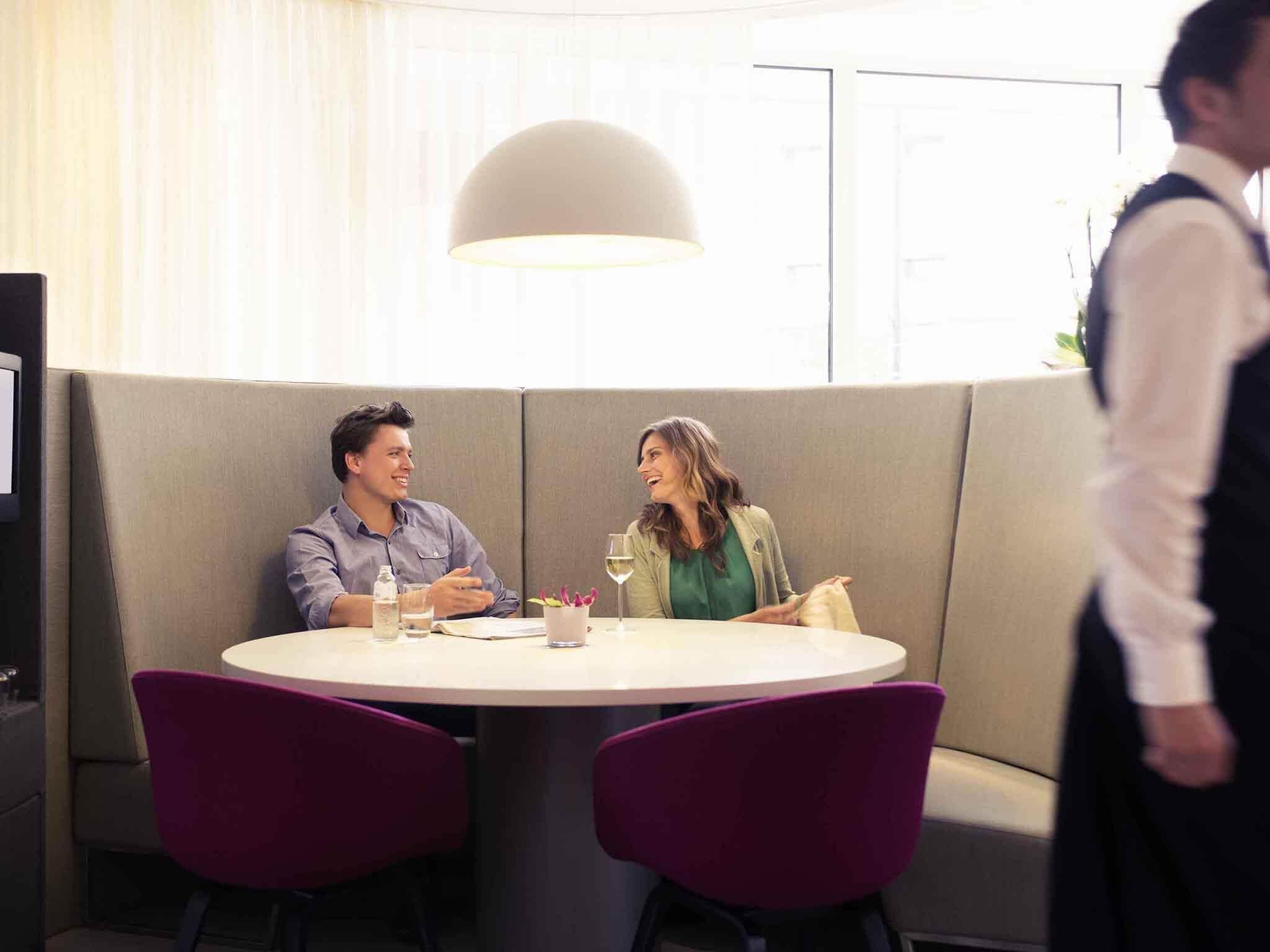 A dining area with a round table, two chairs, a waiter, and a sofa.