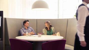 A dining area with a round table, two chairs, a waiter, and a sofa.