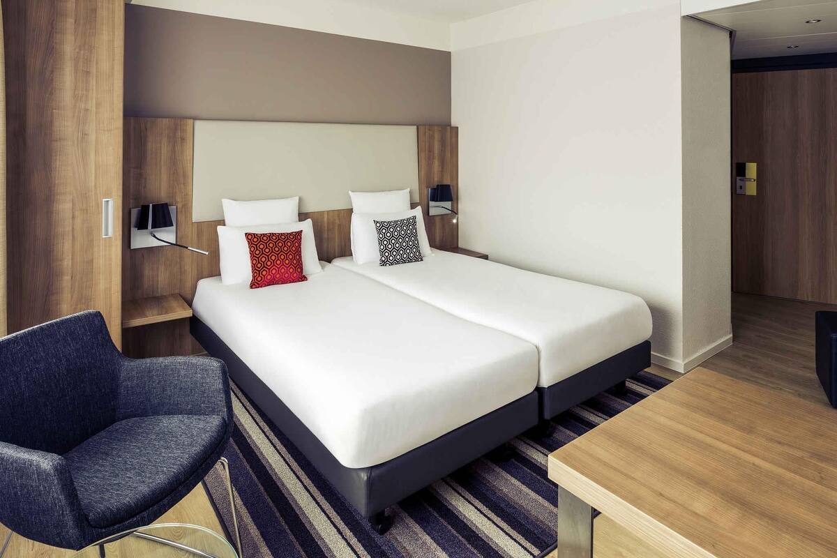 Ein modernes Hotelzimmer mit einem großen Bett, einem Schreibtisch, einem Stuhl und einem Kleiderschrank.