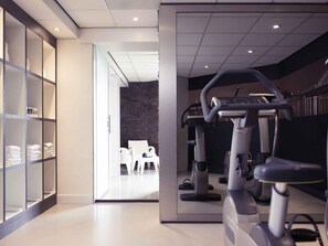 A gym with exercise equipment, a seating area, and a wall with a stone-like texture.