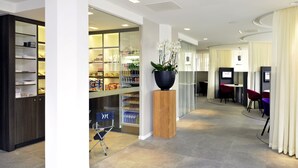 Un moderno vestíbulo de hotel con mostrador de recepción, zona de estar y un bar de aperitivos.