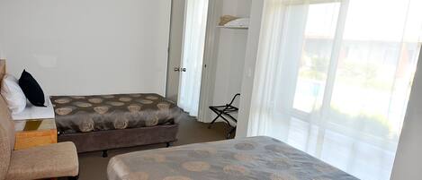 Hotellihuone, jossa on kaksi sänkyä, tuoli, työpöytä ja ikkuna, jossa on verhot.