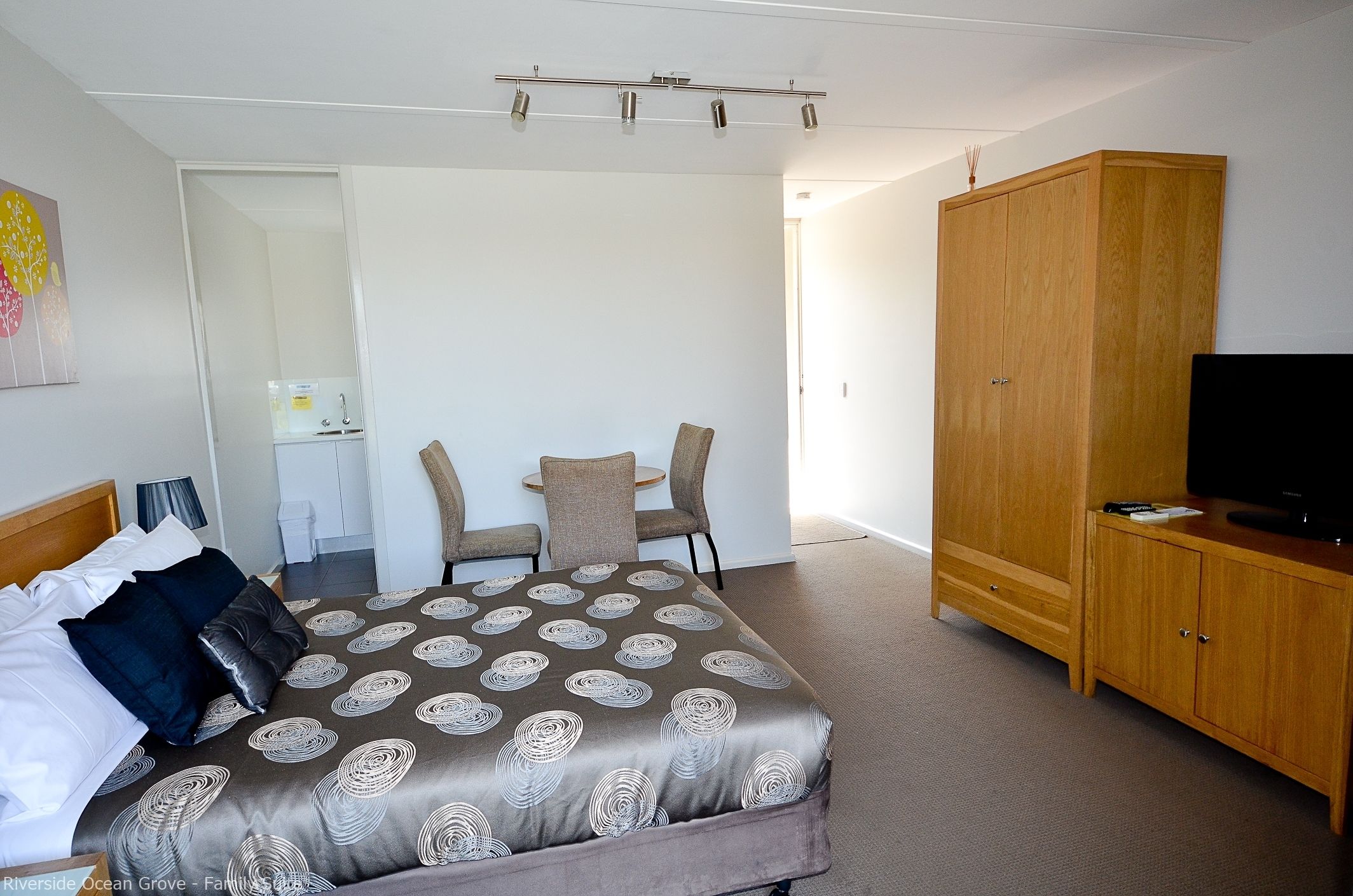 A bedroom with a bed, a TV, a wardrobe, and a desk with a chair.