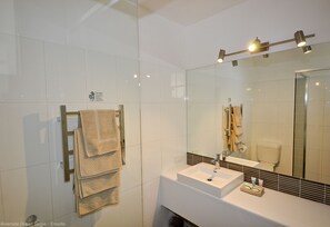 A modern bathroom with a glass shower enclosure, a white sink, and a large mirror.