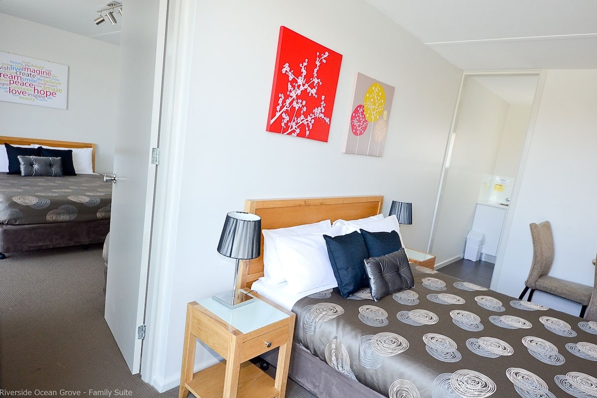 Una habitación de hotel con cama, mesitas de noche, una silla y obras de arte en las paredes.