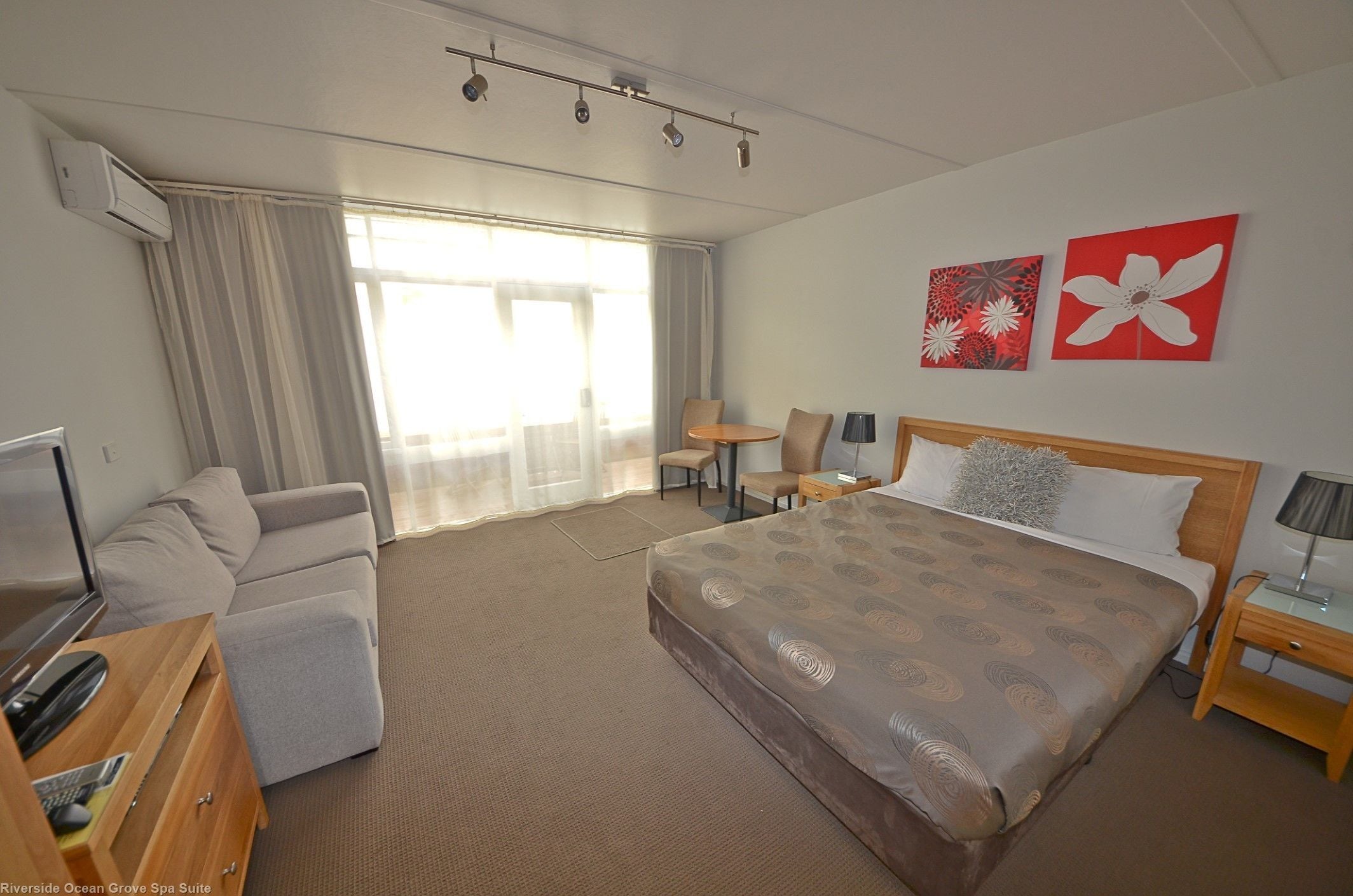 Habitación de hotel con cama, sofá, escritorio, silla y televisión.
