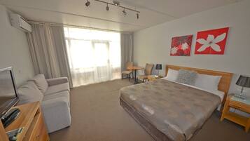 Habitación de hotel con cama, sofá, escritorio, silla y televisión.