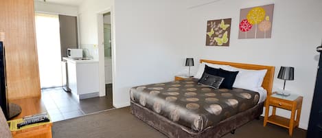 Una habitación de hotel con una cama, mesitas de noche, un escritorio y una televisión.