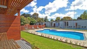 A swimming pool with a wooden deck and a covered area.