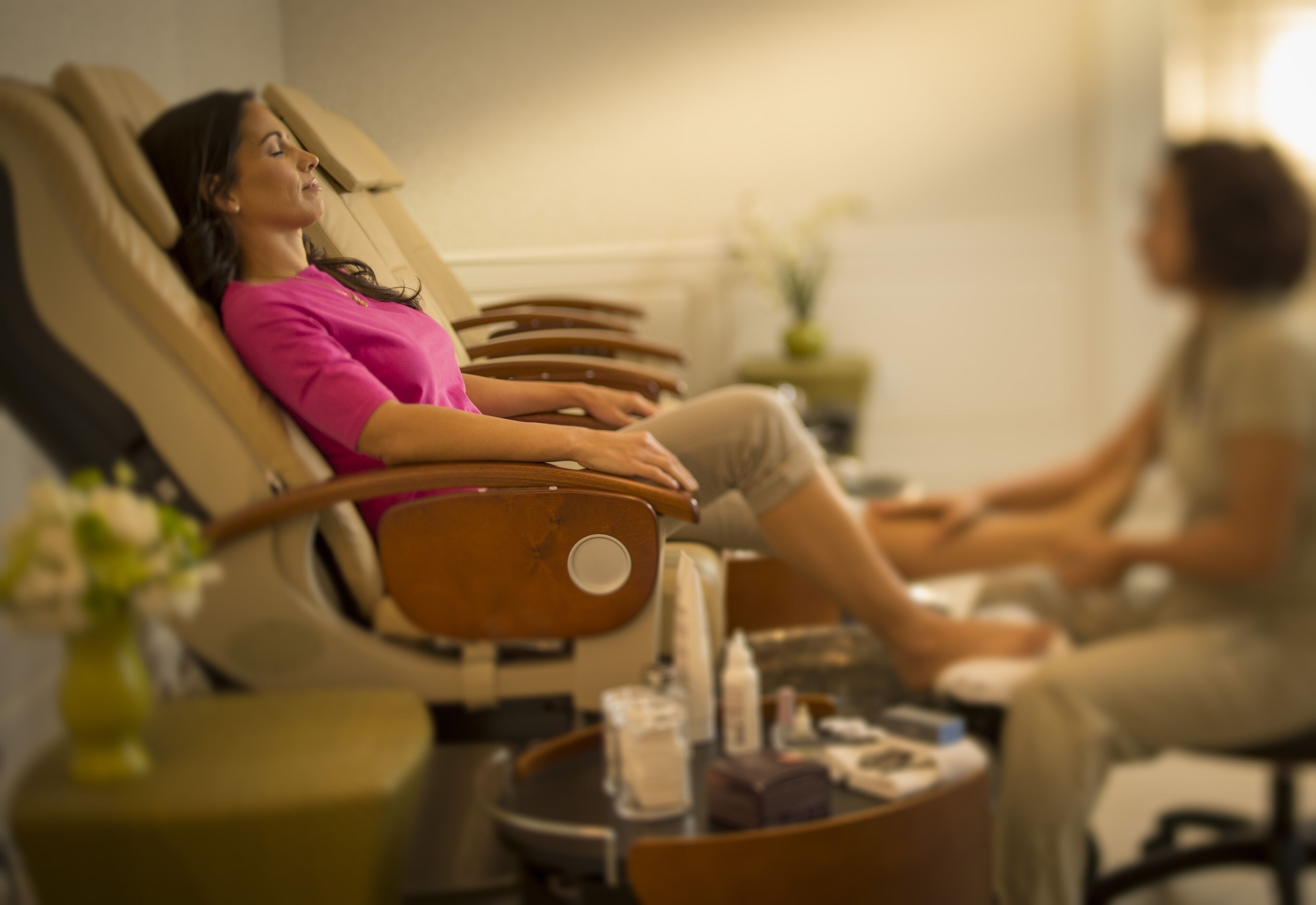Une salle de massage équipée de fauteuils inclinables et d’une petite table ornée d’un vase de fleurs.