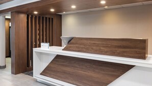 A reception desk with a modern design, featuring a wooden panel and a white counter. - Holiday Inn Express Portland South-Lake Oswego by IHG (Lake Oswego)
