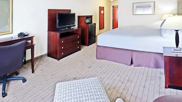 Una camera d'albergo con un letto, una scrivania con una sedia, una televisione, un forno a microonde e un frigorifero.