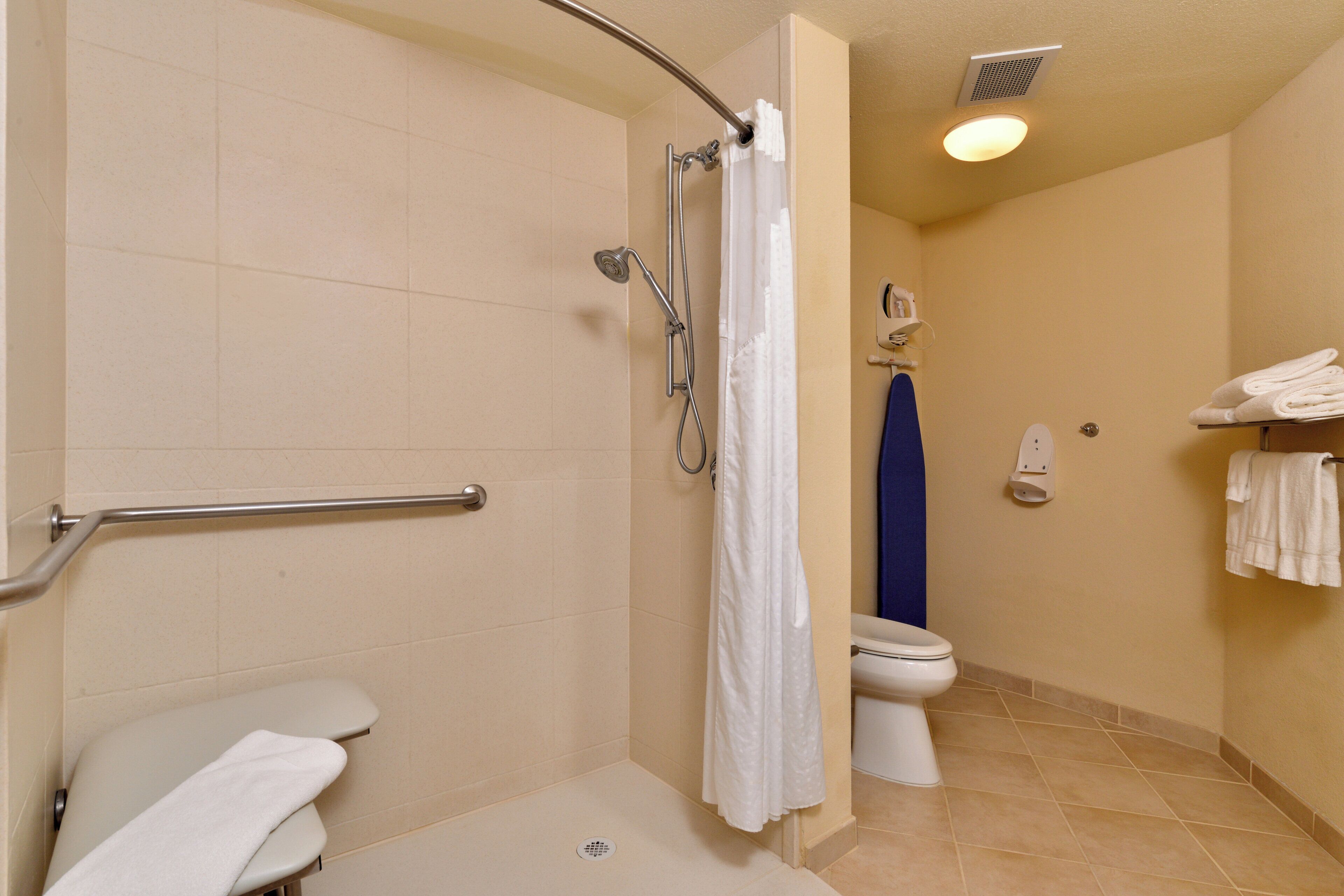 A bathroom with a shower, toilet, and a towel rack.