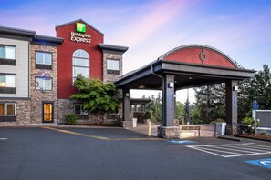 A Holiday Inn Express building with a stone facade, a covered entrance, and a parking lot. - Holiday Inn Express Portland South-Lake Oswego by IHG (Lake Oswego)