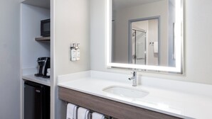 A modern bathroom with a white sink, a large mirror, and a coffee machine. - Holiday Inn Express Portland South-Lake Oswego by IHG (Lake Oswego)