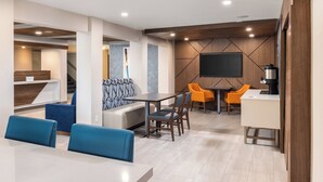 A modern hotel lobby with a seating area, a coffee station, and a flat-screen TV mounted on the wall. - Holiday Inn Express Portland South-Lake Oswego by IHG (Lake Oswego)