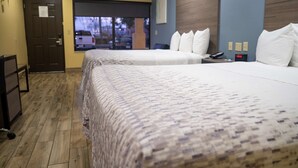 A hotel room with two beds, a wooden floor, a door, and a window with a view of the outside. - Americas Best Value Inn Ft. Myers (Fort Myers)