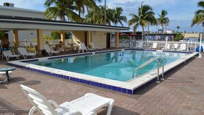 A swimming pool with lounge chairs and a covered seating area. - Americas Best Value Inn Ft. Myers (Fort Myers)