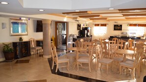 A hotel lobby with a dining area, a reception desk, and a kitchen in the background. - Americas Best Value Inn Ft. Myers (Fort Myers)