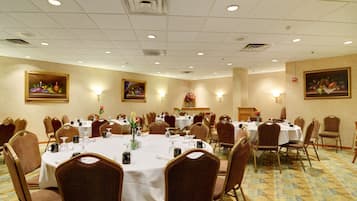 A banquet hall with round tables, chairs, and wall-mounted light fixtures.