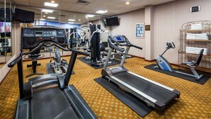 Un gimnasio con cintas de correr, elípticas y equipos de pesas.