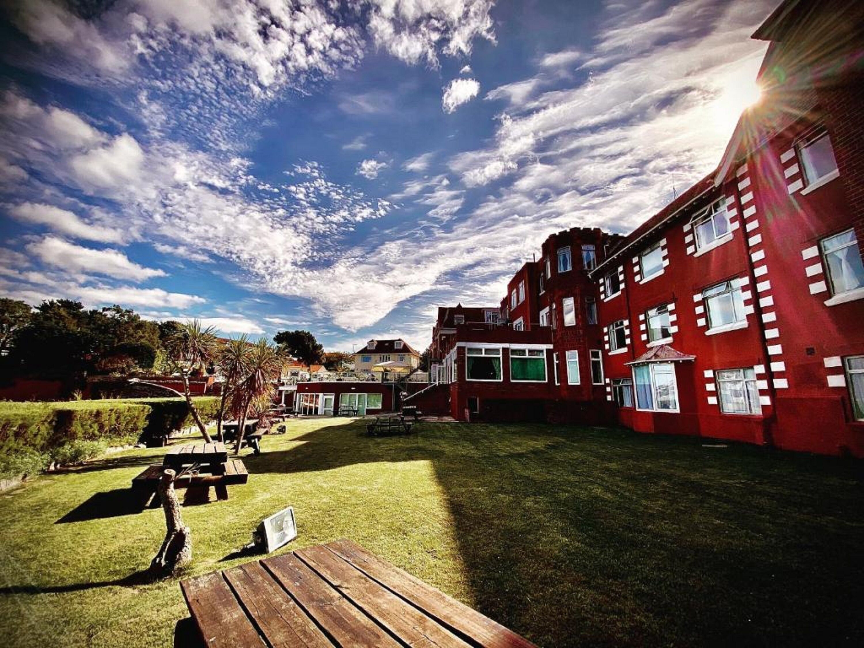 Un patio con edificios de ladrillo rojo, mesas de picnic y una zona verde.