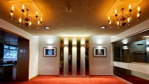 A spacious room with a red carpet, two chandeliers, and a mirrored wall. - Livermead Cliff Hotel (Torquay)