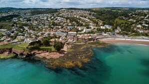 An aerial view of a coastal town with residential buildings, a beach, and rocky outcrops. - Livermead Cliff Hotel (Torquay)