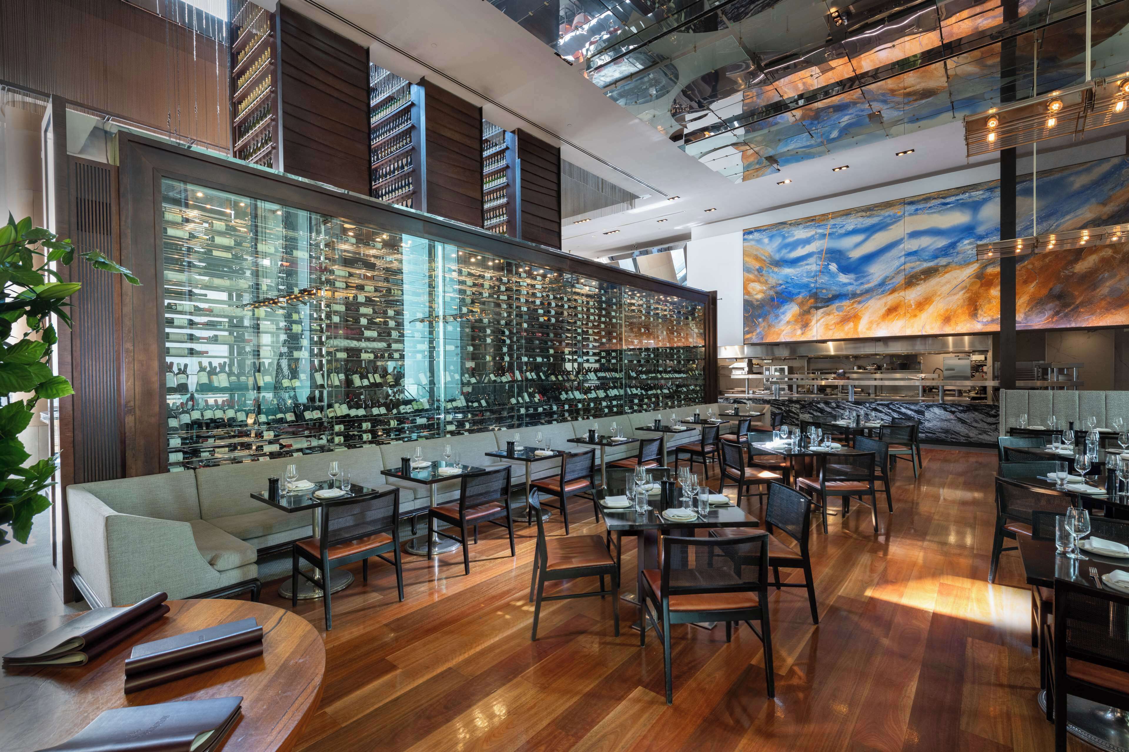 Un restaurante moderno con bodega de vinos, suelos de madera y un mural grande.