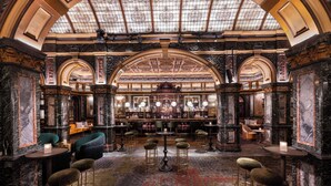 Un interior opulento con paredes de mármol, un techo alto y una zona de bar central.