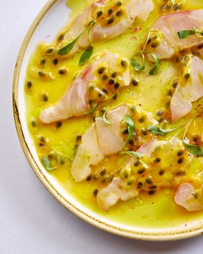 A plate of food with a creamy yellow sauce, green leaves, and black seeds.