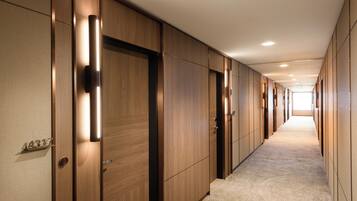 A hallway with wooden doors, numbered room signs, and a carpeted floor.