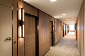 A hallway with wooden doors, numbered room signs, and a carpeted floor. - Hilton Sydney (Sydney)
