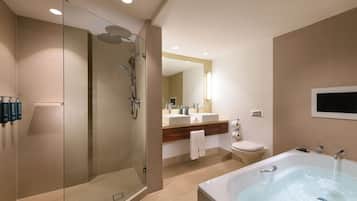 A modern bathroom with a glass-enclosed shower, a large bathtub, a vanity with two sinks, and a toilet.
