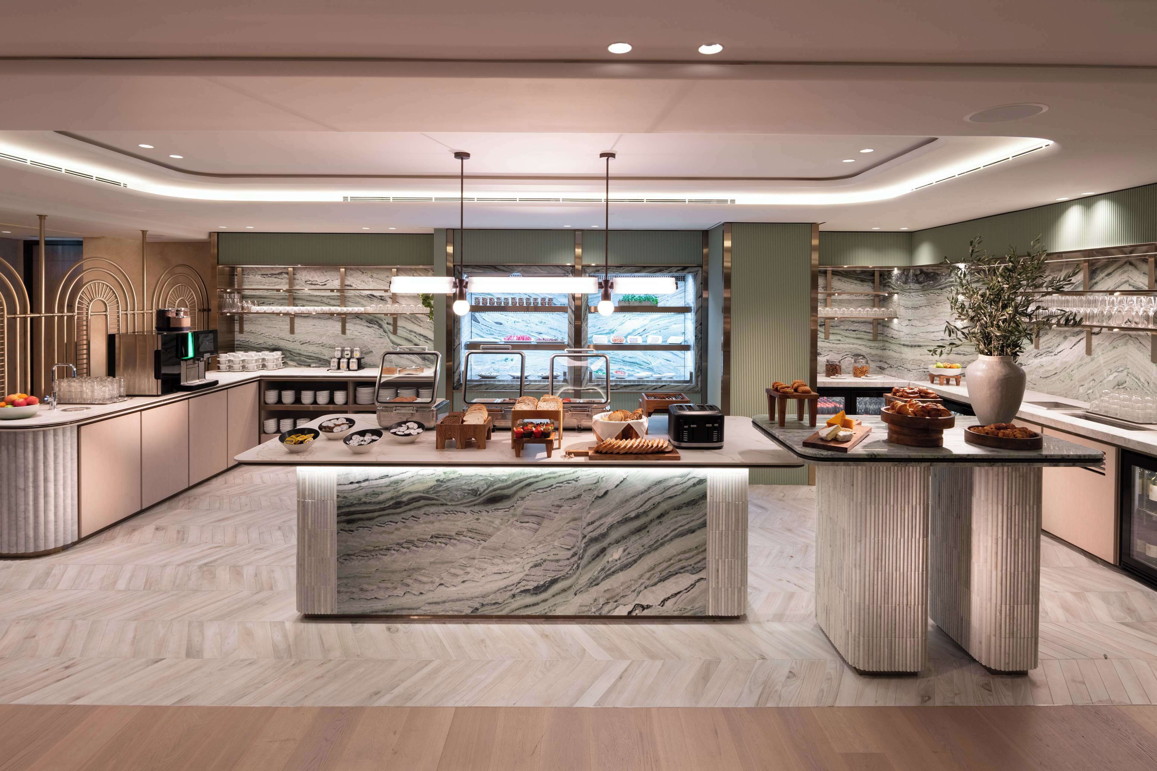 A modern kitchen with marble countertops, a central island, and a view of the city through a large window.