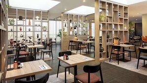 Un restaurante moderno con techos altos, luz natural y diversas opciones de asientos.