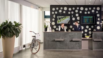 Ein Empfangsbereich mit modernem Design, ausgestattet mit einem Empfangstresen, zwei Bildschirmen und einem Fahrrad.