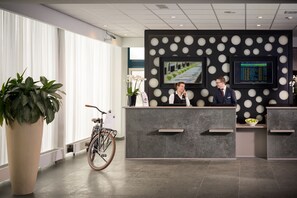 Un área de recepción de diseño moderno, con mostrador de recepción, dos monitores y una bicicleta.