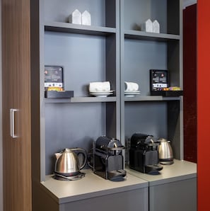 Una kitchenette con cafetera, hervidor y microondas sobre la encimera.
