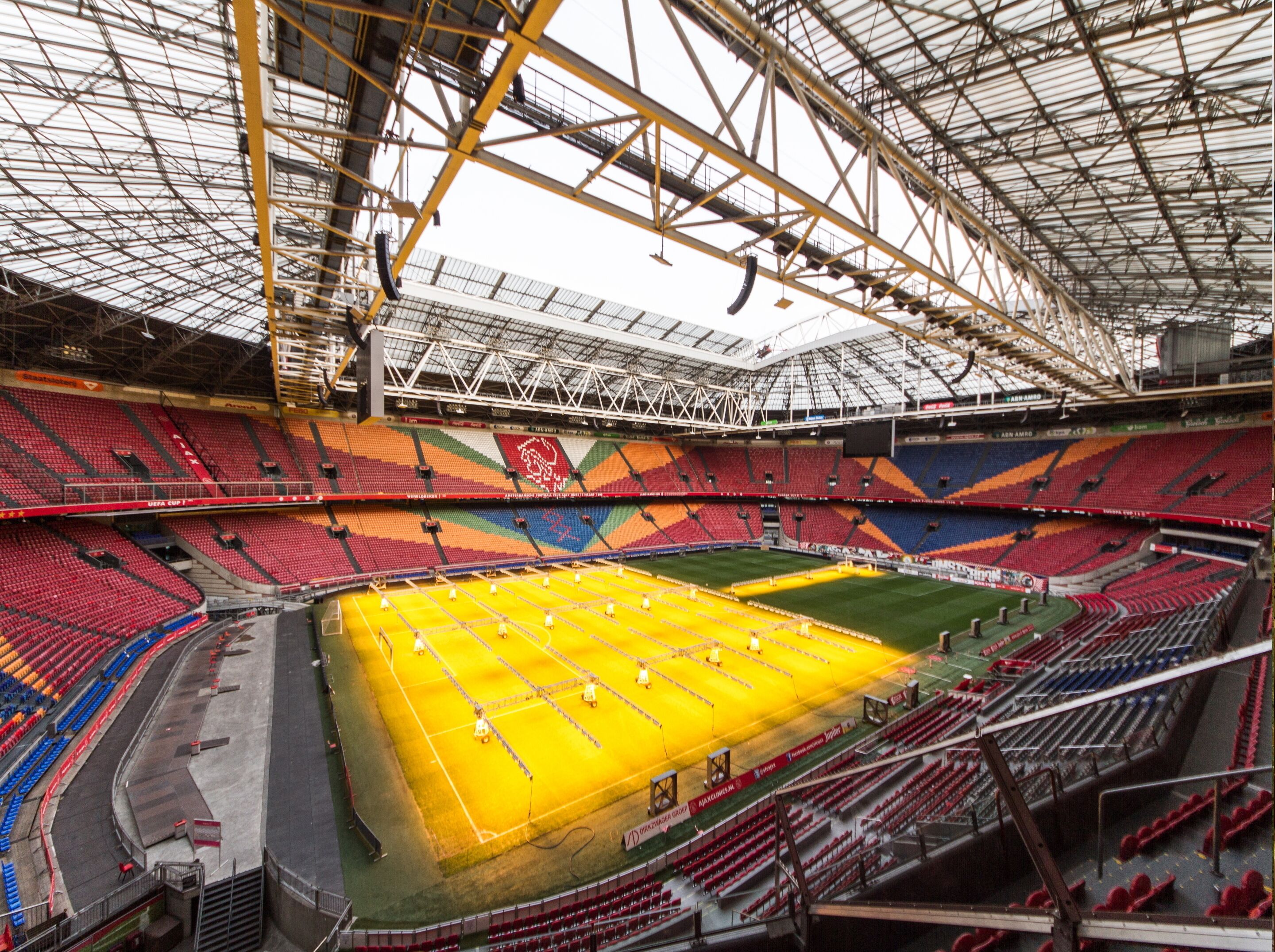A large stadium with multiple tiers of seating, a central field, and a high ceiling with structural beams.