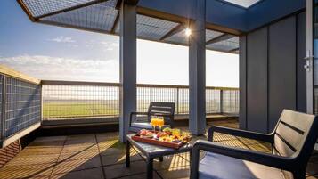 Una terraza con mesa lista para el desayuno, una silla y vistas al cielo.