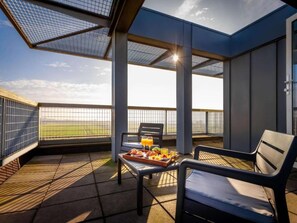 Una terraza con mesa lista para el desayuno, una silla y vistas al cielo.