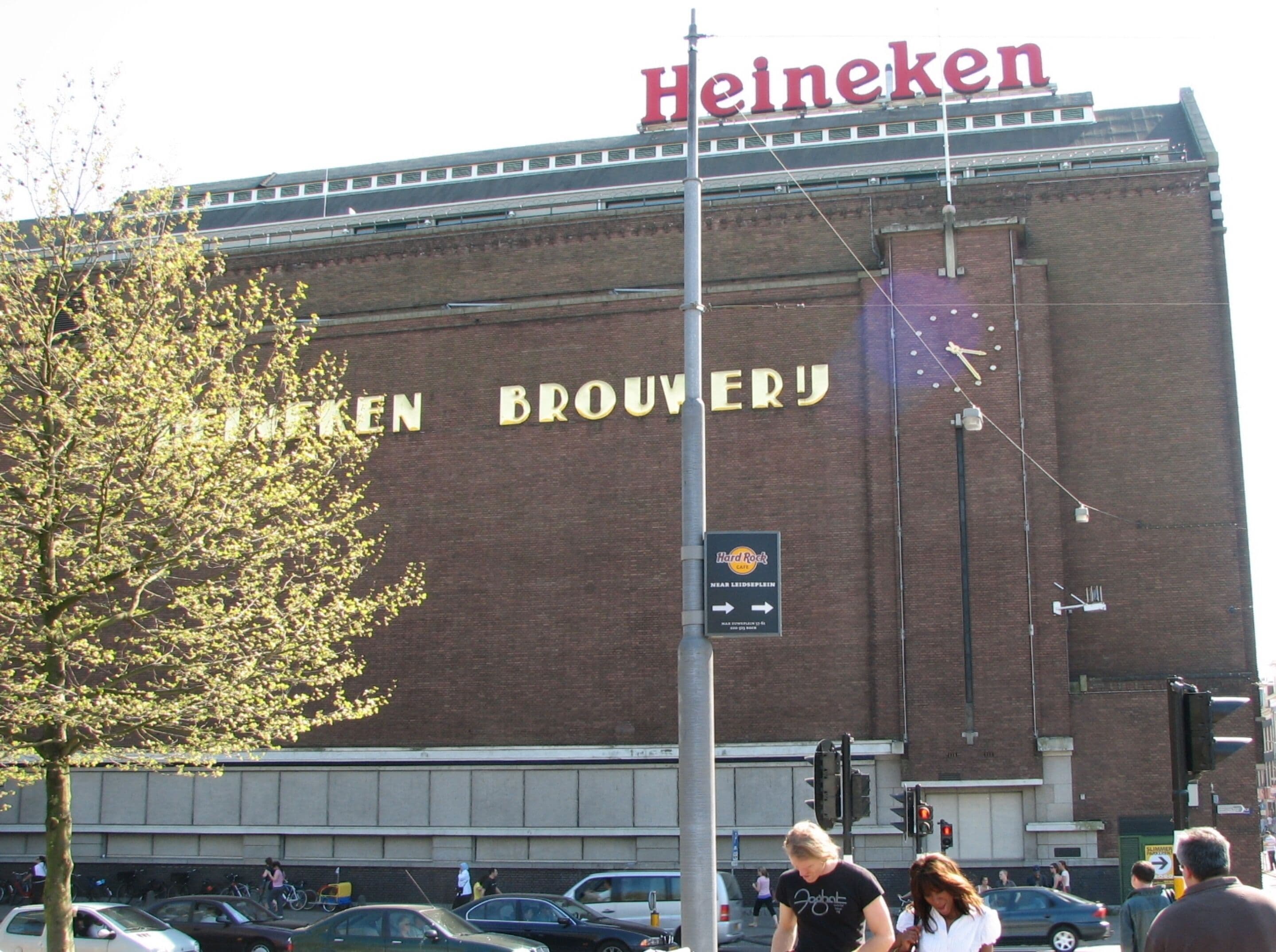 A large brick building with "Heineken" and "Heineken Brouwerij" signage, a street sign, and a traffic light.
