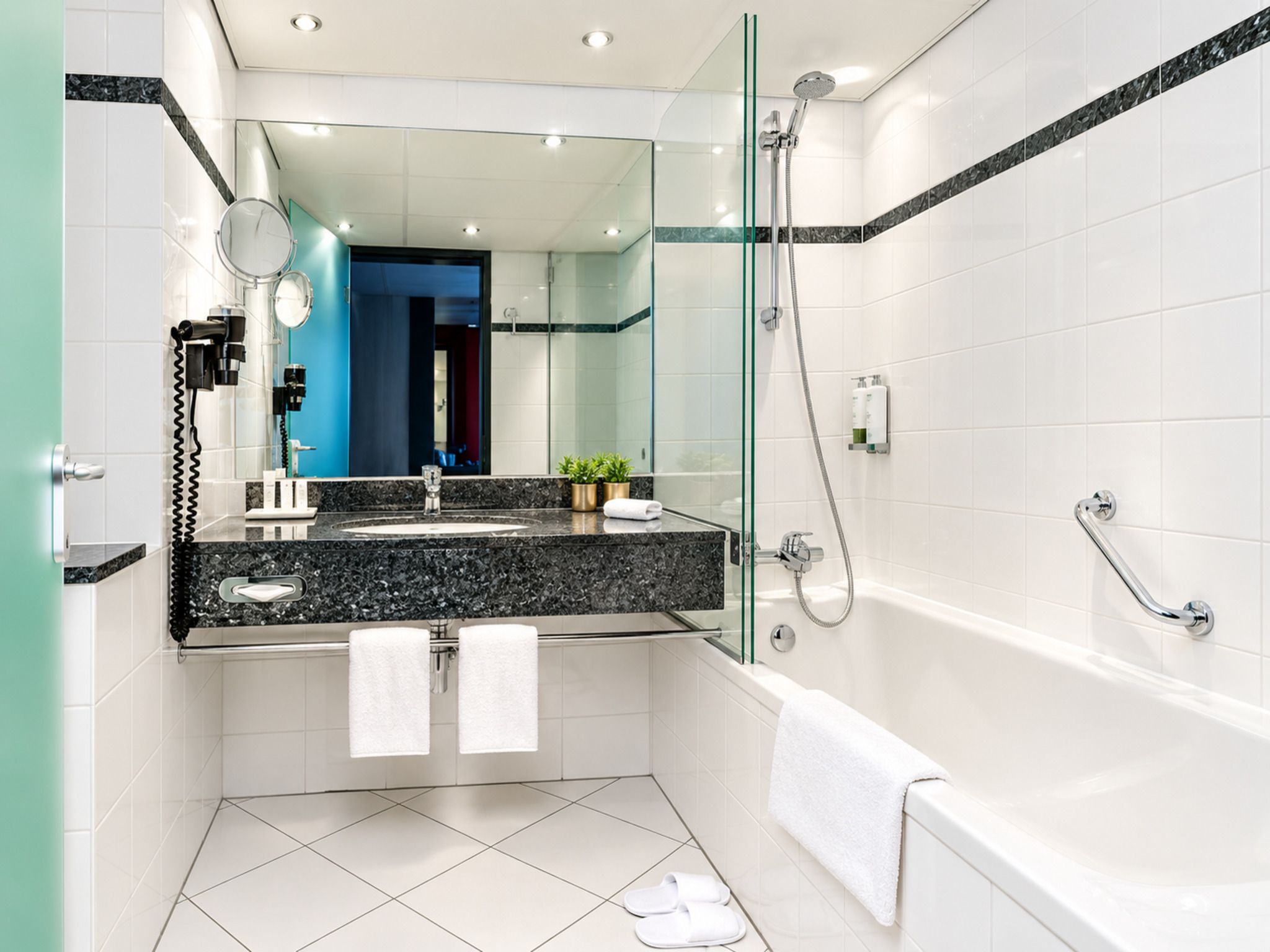 Un bagno moderno con doccia vetrata, lavabo in marmo e vasca da bagno.