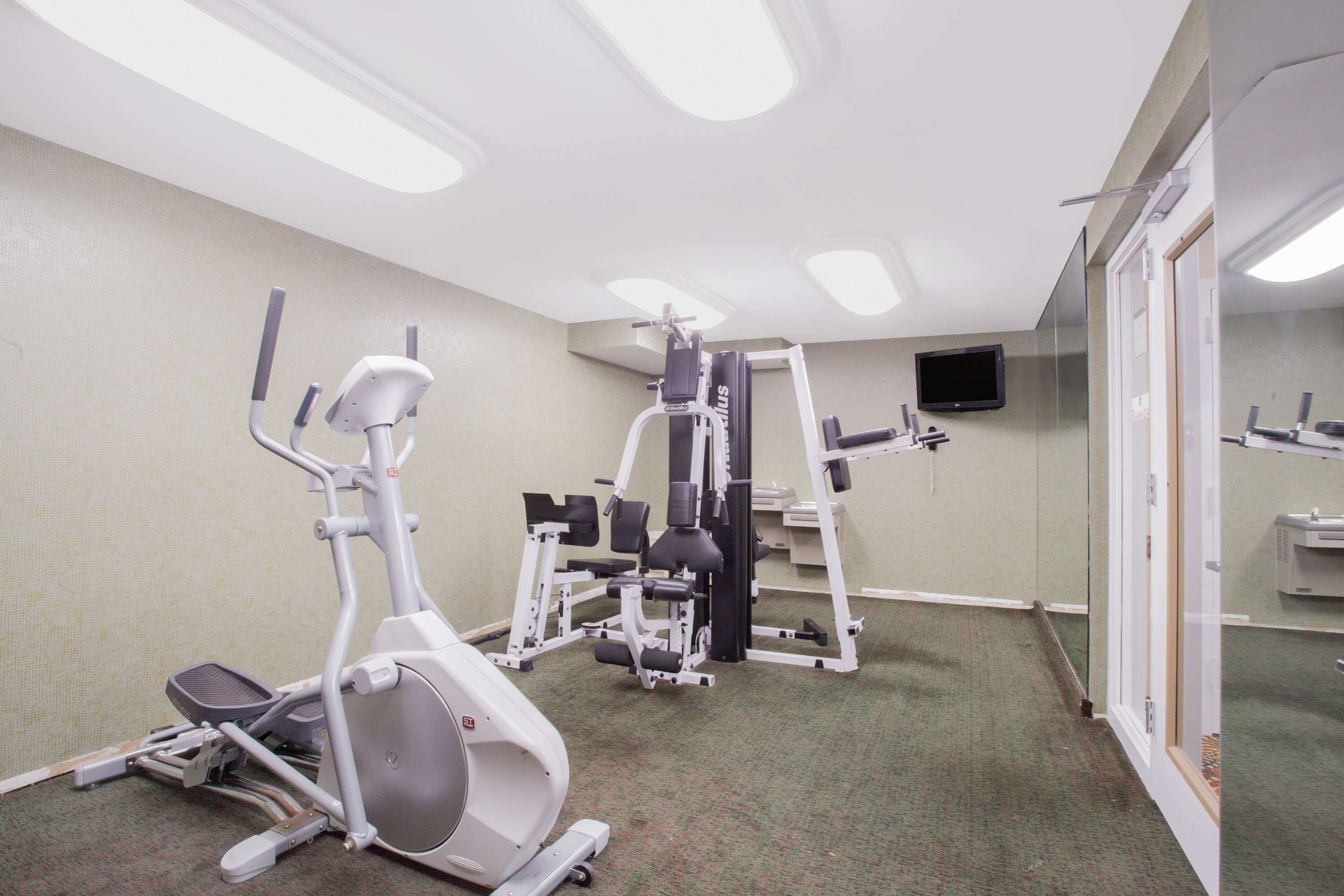 Une salle de remise en forme équipée de matériel d’exercice, d’un téléviseur et dotée d’un sol recouvert de moquette.