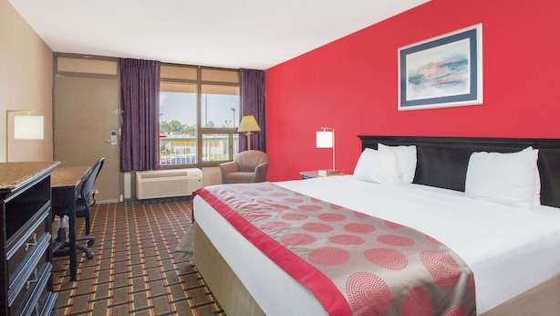 A hotel room with a large bed, a desk, and a chair. - Ramada Hotel & Conference Center by Wyndham Edgewood (Edgewood)