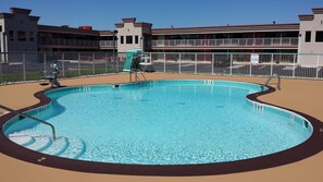 A swimming pool with clear water, surrounded by a fence and a building in the background. - Ramada Hotel & Conference Center by Wyndham Edgewood (Edgewood)