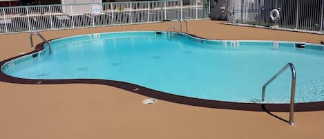 A rectangular swimming pool with a black edge and metal handrails.