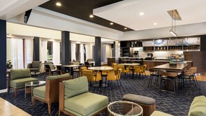 A hotel lobby with seating areas, a bar, and a kitchenette.