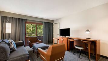 Une chambre d’hôtel équipée d’un canapé, d’un fauteuil, d’un bureau et d’une télévision.